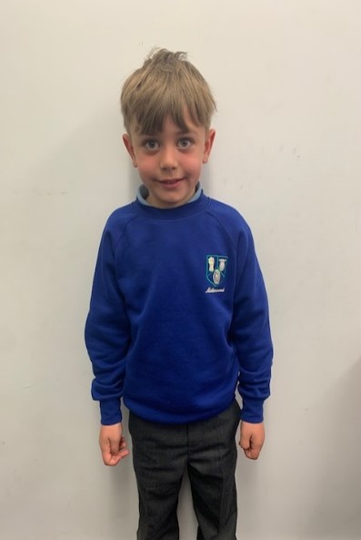 boy wears blue jumper with dark grey trousers